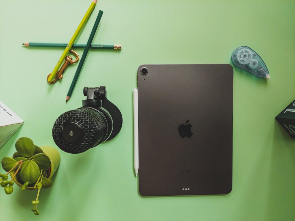 An ipad, a pen, and a pencil on a green table